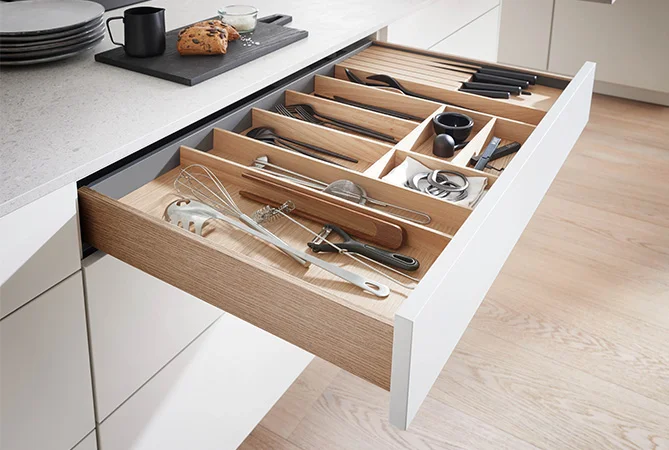 Lade-indeling in SENSO 488 Alpine wit biedt overzicht met houten inzetstukken en snelle toegang tot keukengerei. Lichtgekleurd front SENSO 488 in wit creëert een vriendelijke sfeer met veel opbergruimte voor kleine kamers met daglicht.