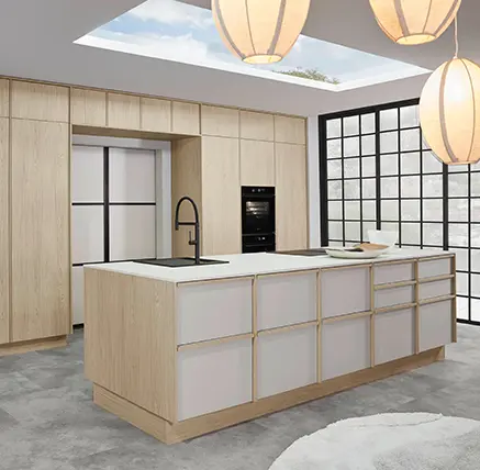 Helle Küche mit Fronten in Holzoptik und Kücheninsel mit cremefarbenen Schubladen, dahinter Sprossenfenster und ein Oberlicht.