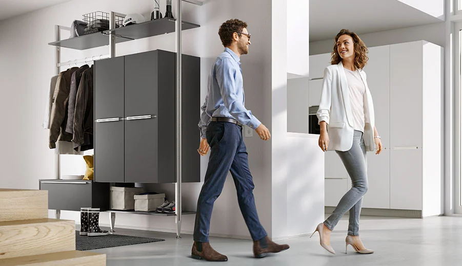 Zwei Personen führen einen freundlichen Austausch an einem schlanken, modernen Kleiderschrank, der die effiziente Nutzung von Raum und zeitgemäßes Innendesign hervorhebt.
