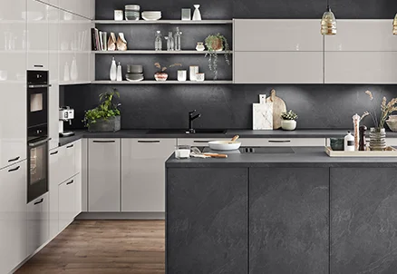 Zeitgemäße Küche mit schwarzen Arbeitsplatten, weißen Schränken, stilvollen Pendelleuchten und einem Fenster mit Blick auf grünes Laub.