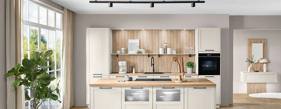 Moderne, helle Küche mit Holzregalen, Edelstahlgeräten und stilvollem Wasserhahn. Viel Licht durch große Fenster.