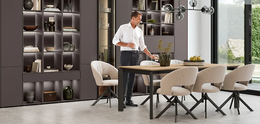 Coin repas moderne avec fauteuil TURN II - stylé, confortable et parfaitement combiné avec des étagères de salon ouvertes et un éclairage d'ambiance.