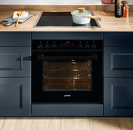 Vista dettagliata del piano cottura nella cucina nobilia con frontale Cascada 778 in blu fiordo. Il piano cottura da incasso è armoniosamente integrato nelle basi blu e abbinato a un moderno piano cottura.