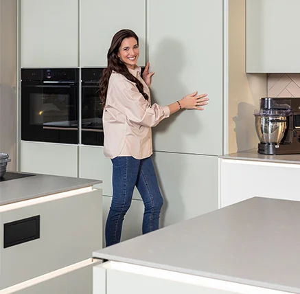 Sally ist in einer modernen Küche mit hellen Fronten und integrierten Hochschränken zu sehen. Das Bild zeigt stilvolles Küchendesign mit zeitgemäßer Wohnlichkeit.
