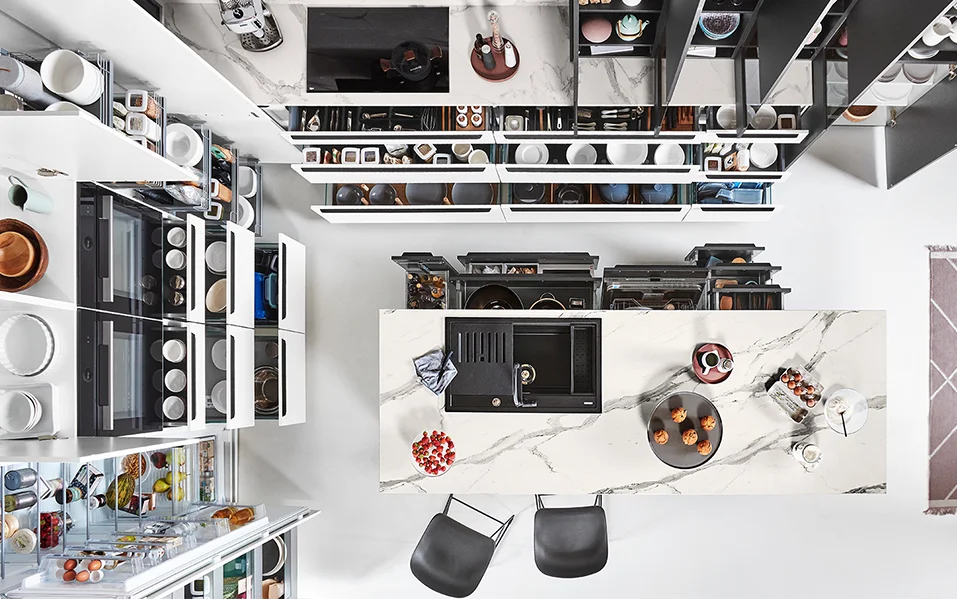 L-shaped kitchen with marble-look worktop, efficient storage space concept and fully open pull-outs, photographed from a bird's eye view.