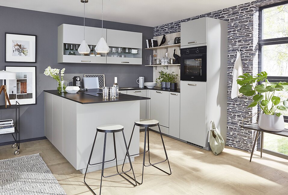Kompakte U-Küche mit Front TOUCH 341 in Steingrau supermatt, funktional gestaltet für kleine Räume, moderne Hängeschränke mit Glasfront und stilvolle Insel mit Sitzgelegenheit.