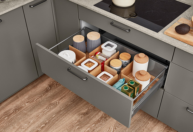 Organizador de cajones de cocina moderno que muestra soluciones de almacenamiento ordenadas con utensilios y recipientes para especias y alimentos secos dispuestos de forma ordenada en un diseño elegante.