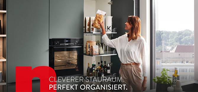 Žena organizuje potraviny v moderní kuchyni s elegantními černými skříněmi, s důrazem na chytrá úložná řešení a organizaci.