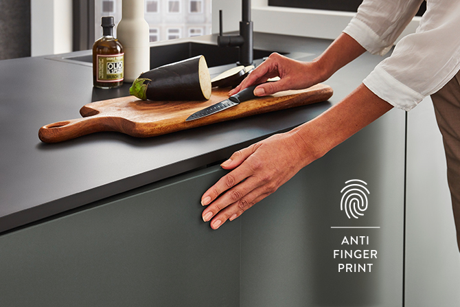 Comptoir de cuisine moderne avec une technologie anti-empreintes digitales, une main d'une personne reposant sur la surface, illustrant le matériau propre et résistant aux traces de doigts.
