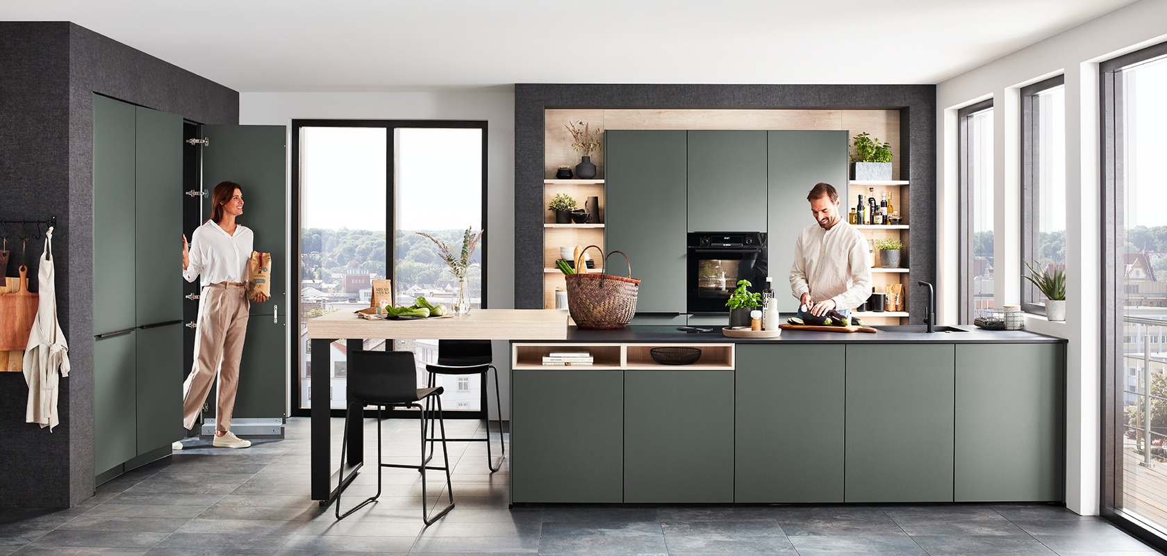 Design contemporaneo della cucina con eleganti armadi verdi, un'isola centrale con posti a sedere e elettrodomestici moderni, valorizzato dalla luce naturale proveniente dalle ampie finestre.