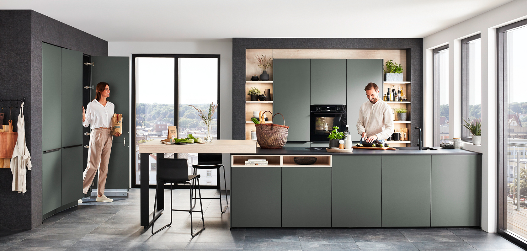 Contemporary kitchen design featuring sleek green cabinetry, a central island with seating, and modern appliances, accented by natural light from expansive windows.