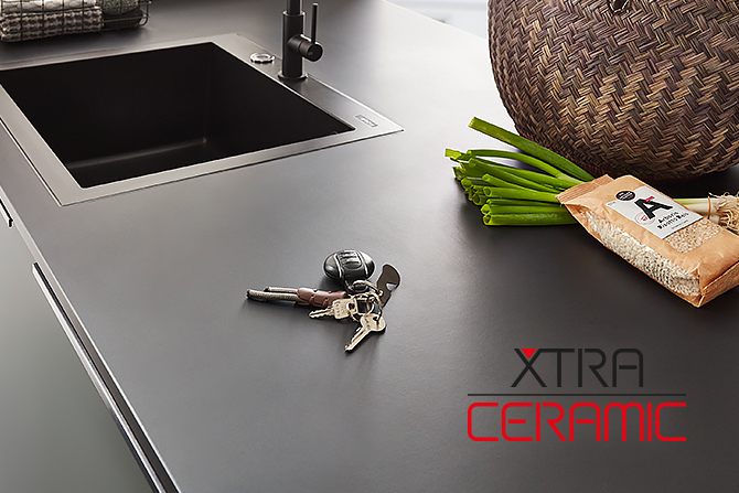 Nowoczesny blat kuchenny z płytą indukcyjną, elegancki design oraz codzienne przedmioty takie jak klucze i zakupy, prezentujący trwałość powierzchni XTRA CERAMIC.
