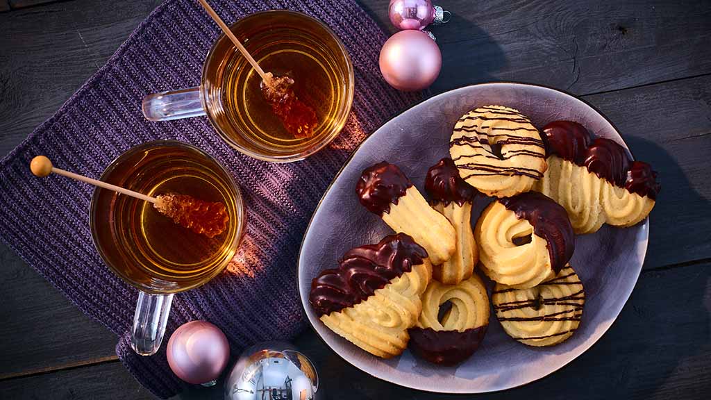 Köstliches Spritzgebäck: Leckere Plätzchen backen, zwischendurch den Teig naschen – in der Weihnachtsbäckerei gibt es manche Leckereien! Denn das Gebäck ist nicht nur ein köstliches Geschmackserlebnis, sondern beinhaltet ausschließlich vegane Zutaten!