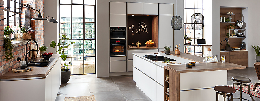 Spacious modern kitchen with sleek appliances, wooden countertops, and stylish shelving, accented by natural light and warm, inviting tones.