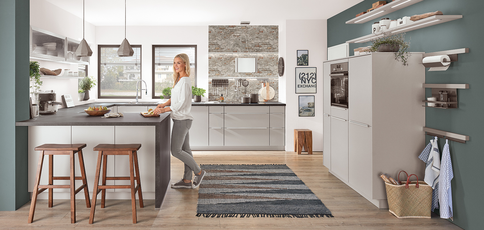 Una cocina moderna con un diseño elegante, que cuenta con una isla central, luces colgantes y acentos de madera, complementada por una mujer interactuando con el espacio.