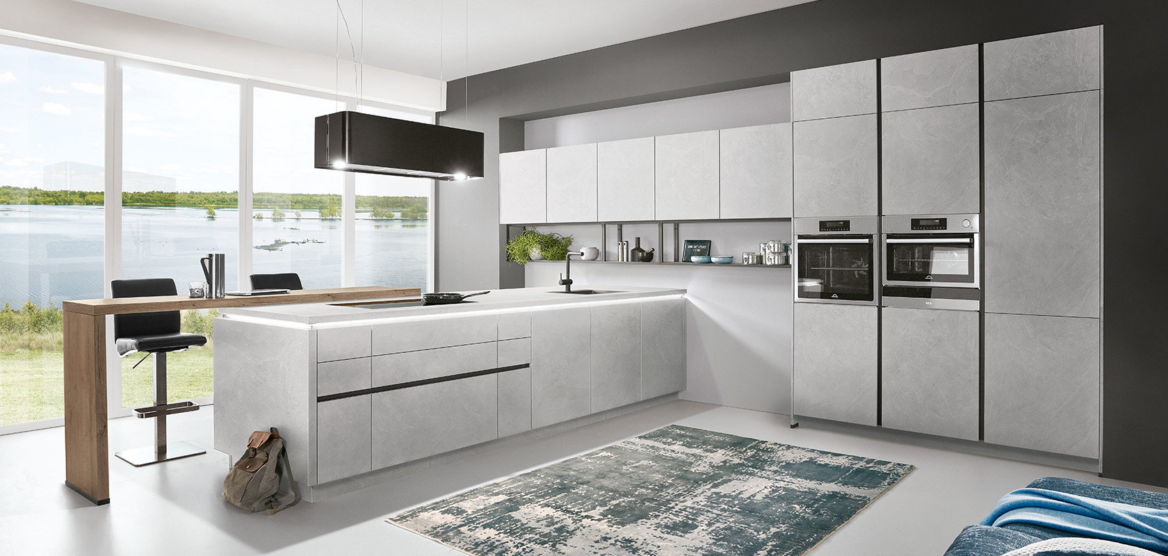 Interior de cocina moderna con elegantes gabinetes grises, electrodomésticos integrados y una isla espaciosa con vista a un lago sereno a través de grandes ventanas.