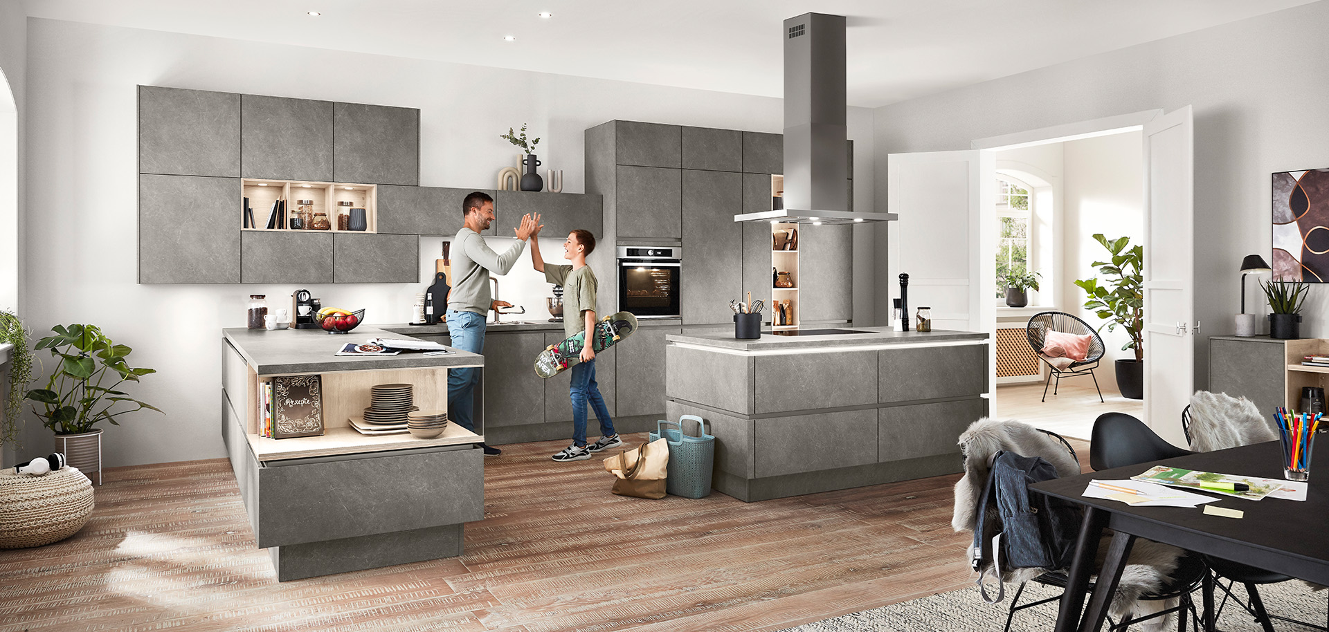 A modern, spacious kitchen with a couple engaged in a cheerful conversation, surrounded by sleek gray cabinetry, and elegant decor under natural lighting.