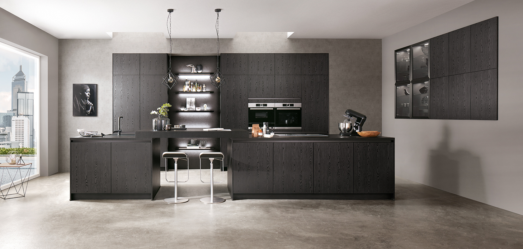 Diseño de cocina moderna con elegantes gabinetes negros, electrodomésticos de acero inoxidable y una isla central con taburetes de bar frente a un fondo de texturas de concreto gris.