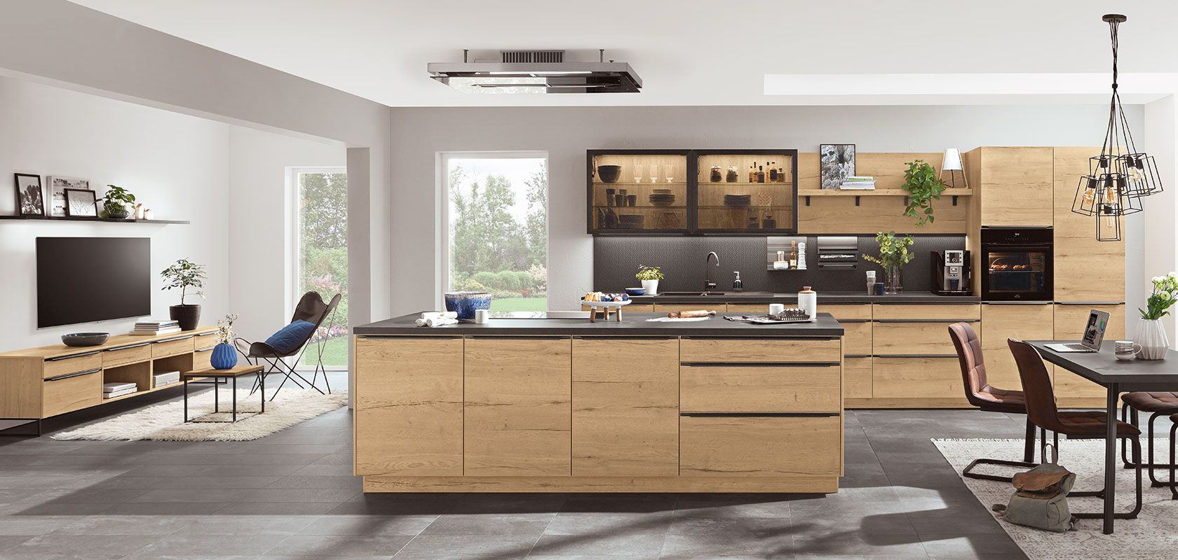 Spaziosa cucina moderna con eleganti armadi in legno, elettrodomestici in acciaio inossidabile e un'ampia isola, che si trasforma senza soluzione di continuità in un'accogliente area soggiorno con luce naturale.