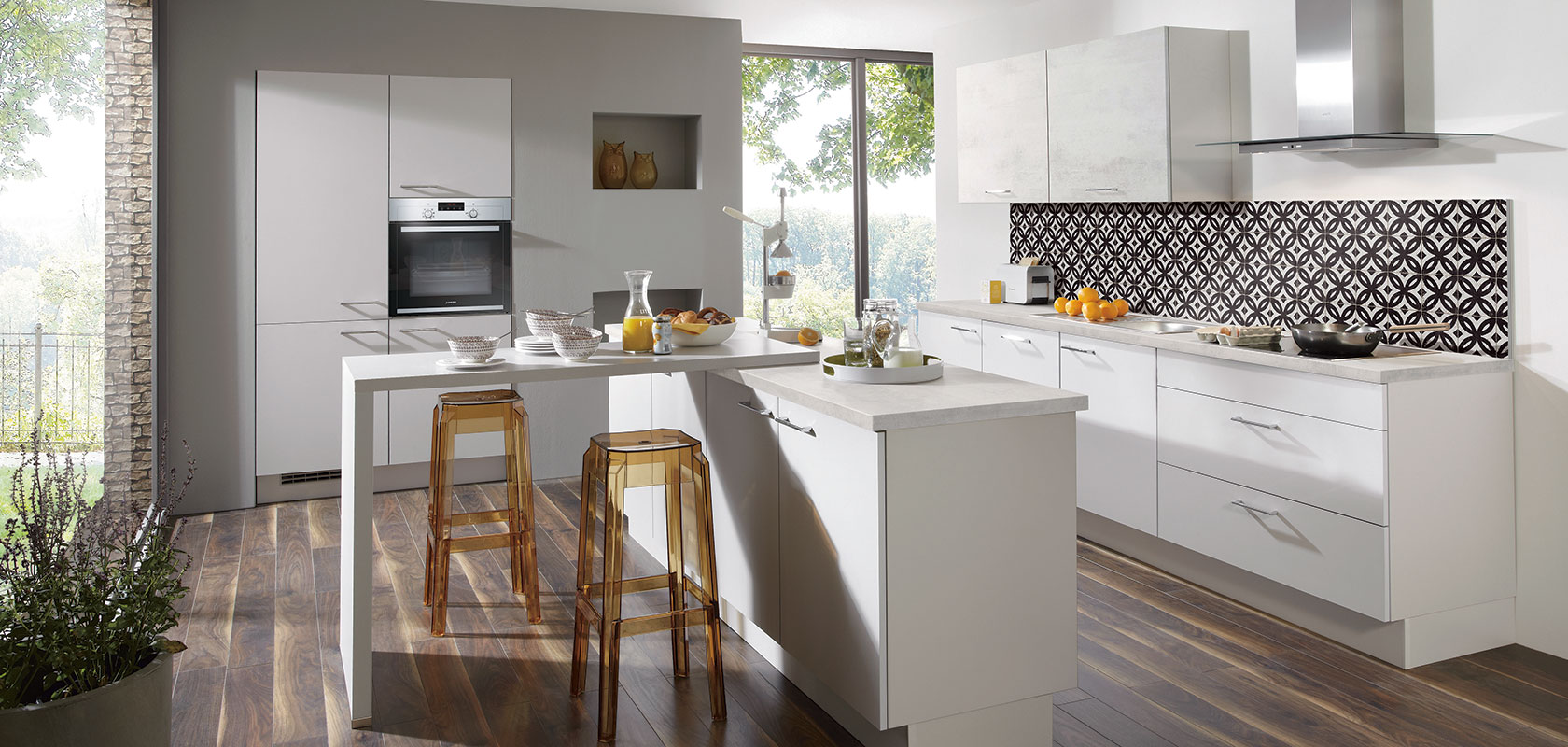 Moderne Küche mit weißen Schränken, Edelstahlgeräten, gemustertem Rückwand, und einer Frühstücksbar mit Hockern neben einem großen Fenster.
