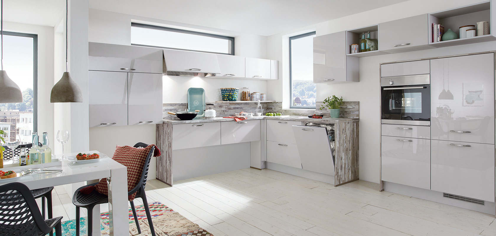 Helle moderne Küche mit weißen Schränken, Edelstahlgeräten und Farbtupfern von dekorativen Gegenständen und einem mehrfarbigen Teppich.