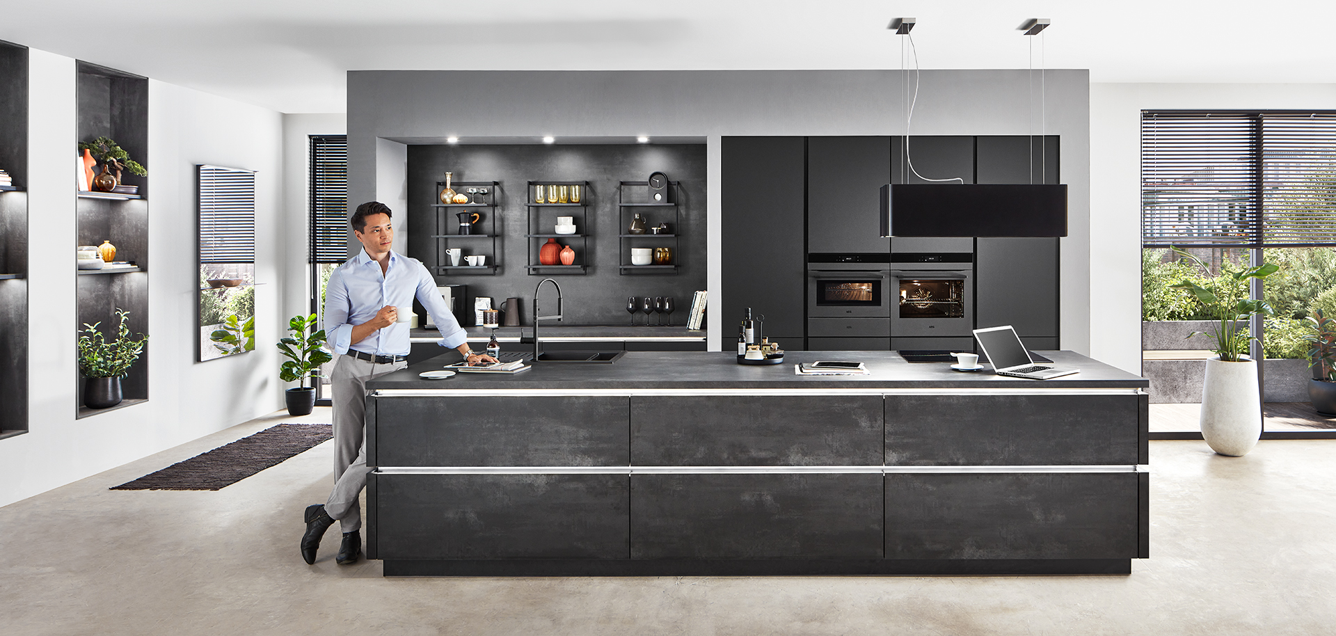 Moderne keukeninterieur met een strak ontwerp met zwarte kasten, ingebouwde apparaten en een persoon die eten bereidt op het kookeiland.