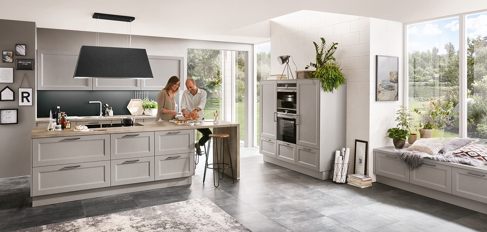 Una cocina moderna y espaciosa llena de luz natural, con electrodomésticos elegantes y una pareja preparando comida juntos en una encimera de isla.