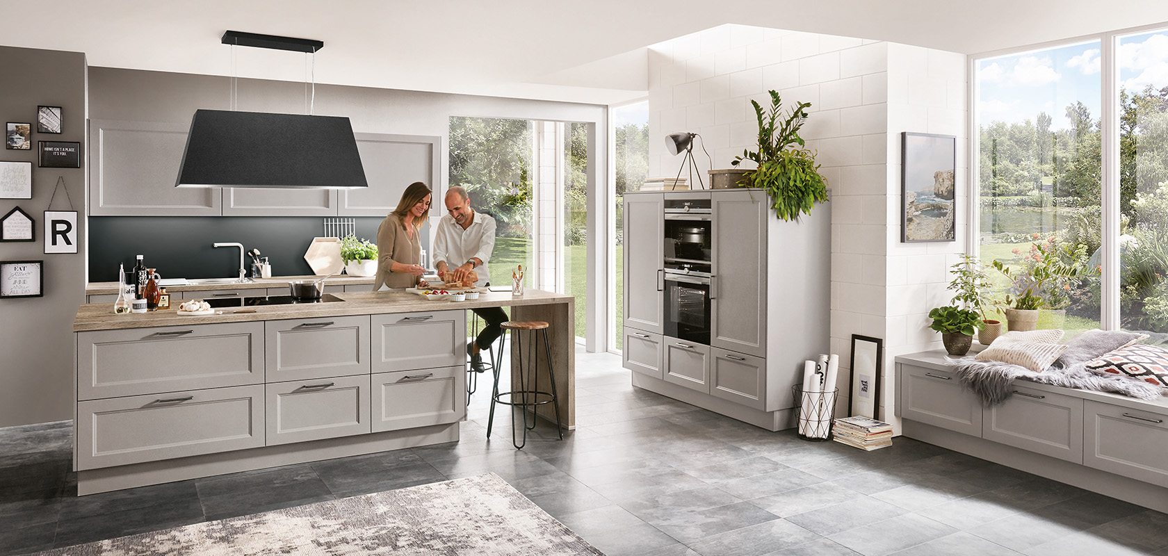 A modern, spacious kitchen filled with natural light, featuring sleek appliances and a couple preparing food together on an island countertop.