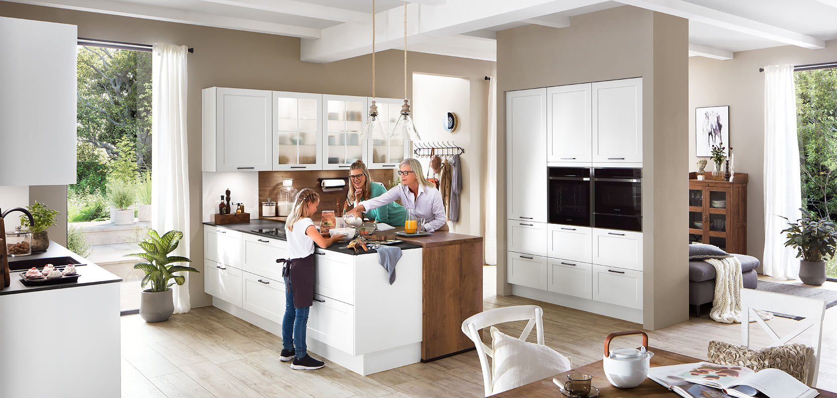 Nowoczesna kuchnia wypełniona naturalnym światłem, w której rodzina spędza czas razem, prezentująca eleganckie białe szafki kuchenne i stalowe urządzenia.