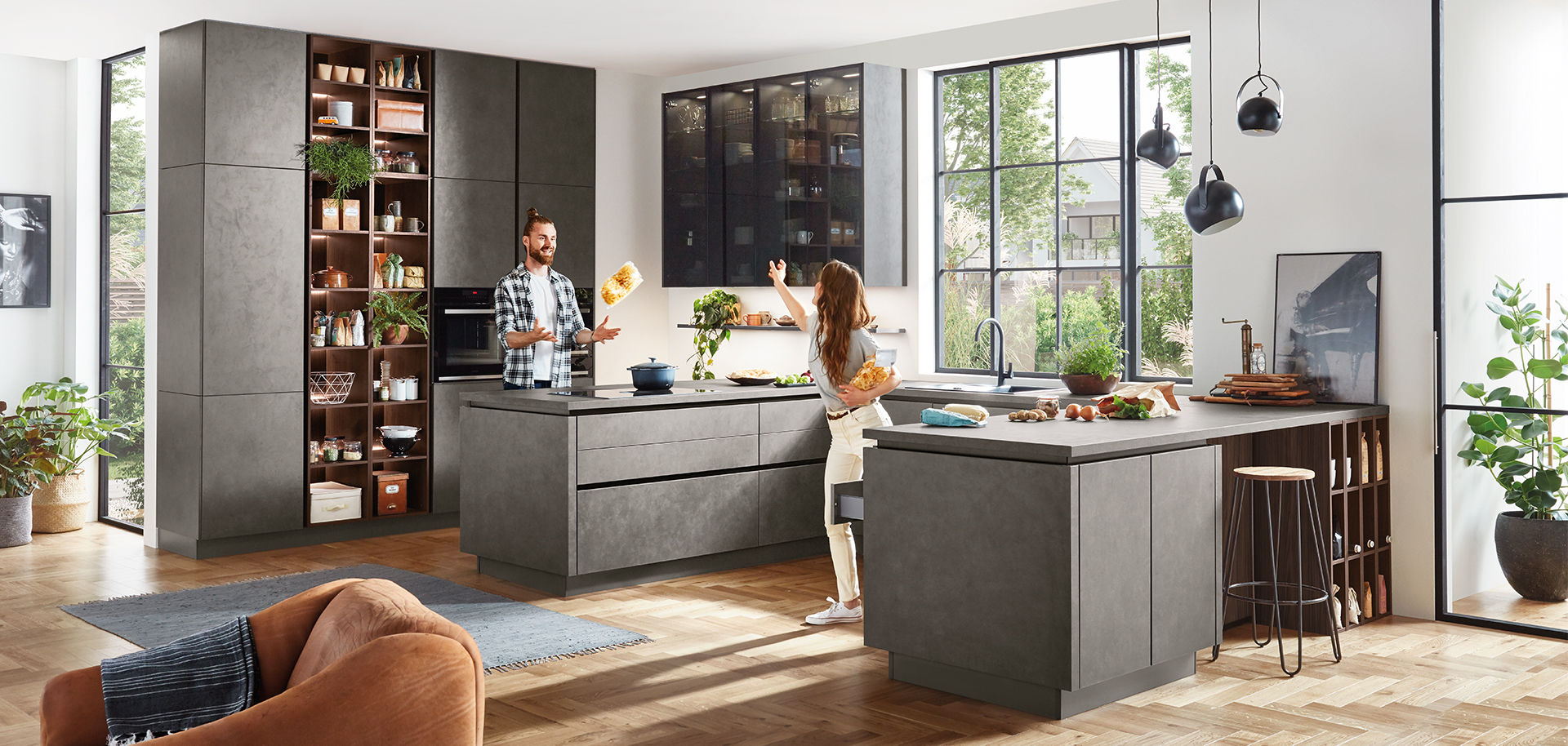 Modern kitchen design with sleek gray cabinetry, integrated appliances, and a central island. A couple enjoys cooking in the well-lit, spacious interior.