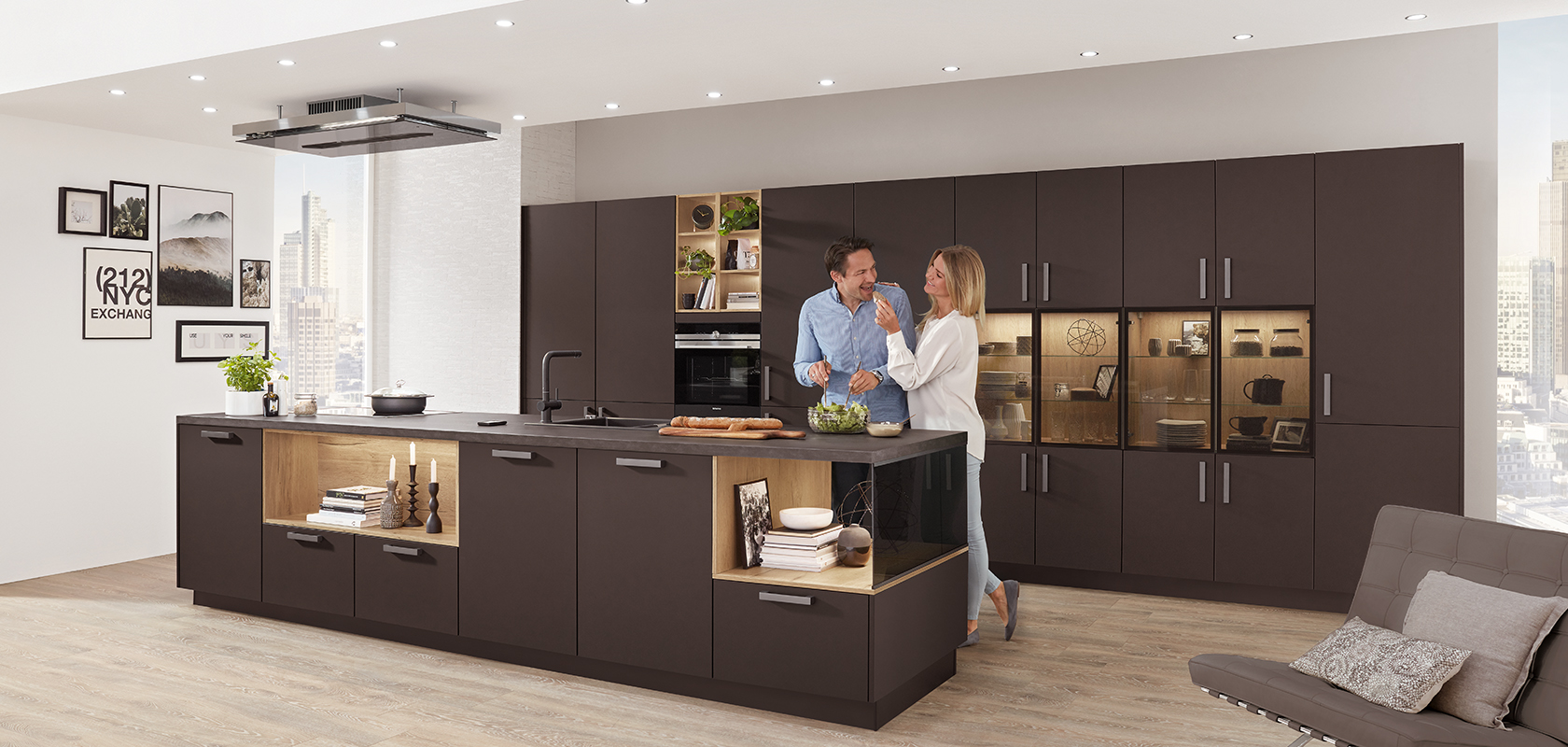 Une cuisine moderne avec un couple cuisinant ensemble, comprenant des armoires sombres élégantes, des appareils intégrés et un îlot spacieux avec un agencement à concept ouvert.