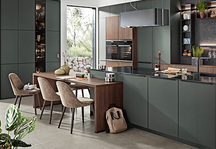 Moderne nobilia Küche mit integriertem Essbereich, eleganten Elektrogeräten und Fronten in dunklem Grün mit Holzakzenten. Ideal für offenes Wohnen mit Stil und Funktion.