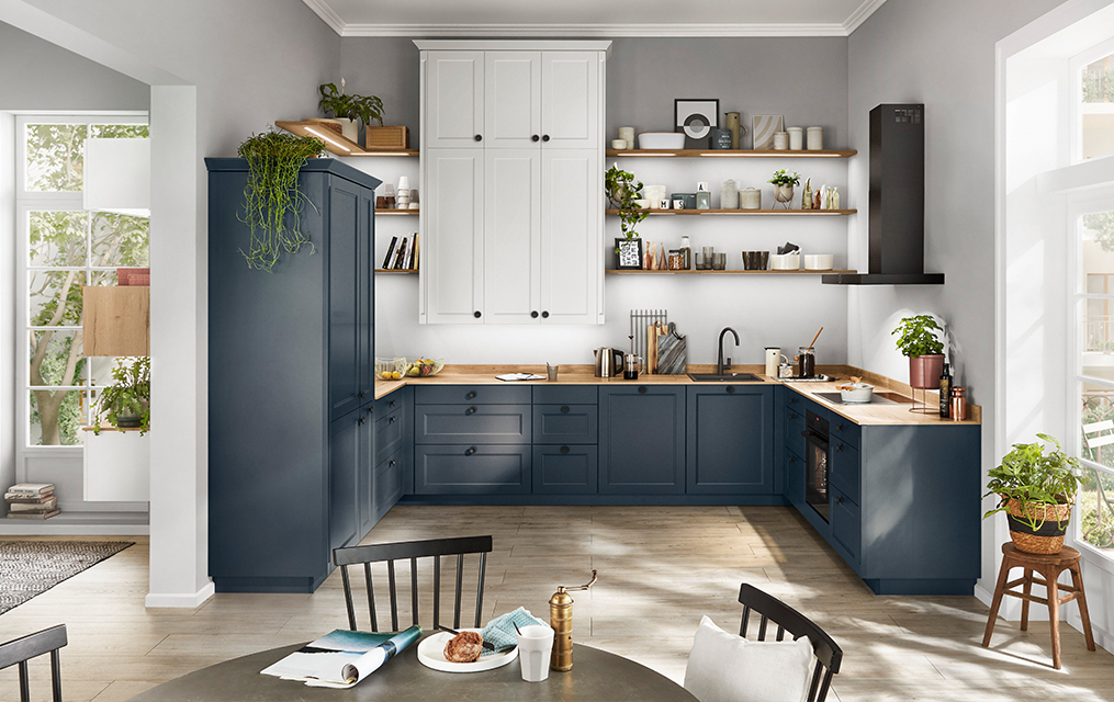 Cucina contemporanea con armadi blu, piani in legno e elettrodomestici eleganti in uno spazio luminoso e arioso con luce naturale.