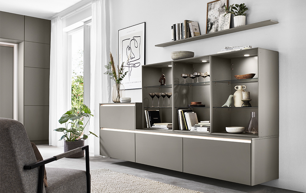 Interni moderni del soggiorno con eleganti unità di scaffalature modulari, esponendo libri e decorazioni, completati da mobili minimalisti e luce naturale.