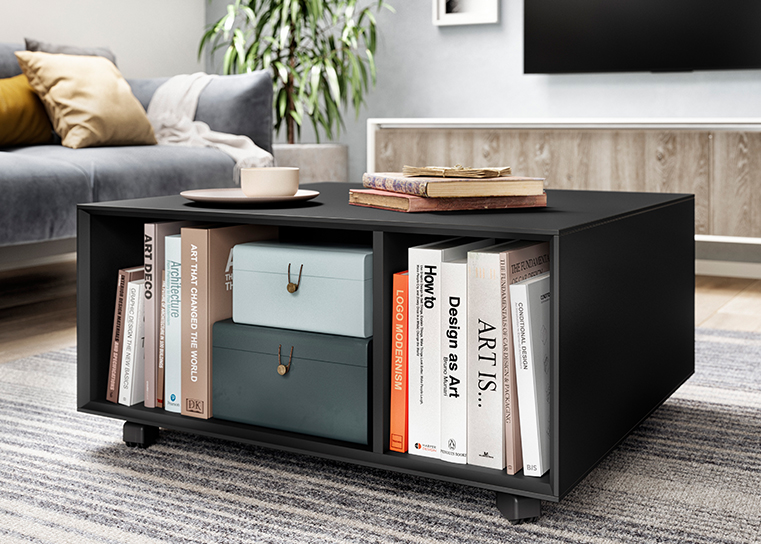 Interior moderno de una sala de estar con una elegante mesa de café negra con libros y objetos decorativos, complementando un acogedor sofá en el fondo.