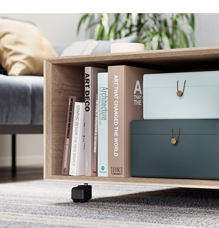 Modern wooden bookshelf with a selection of books on art and design alongside stylish storage boxes in a cozy living room setting.