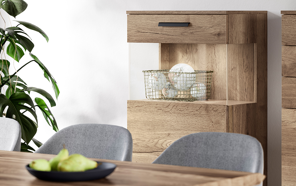 Intérieur de salle à manger moderne avec des chaises grises élégantes, un buffet en bois et des plantes décoratives, mettant en valeur un design minimaliste et des textures naturelles.