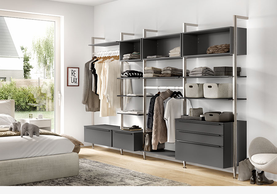 Nowoczesna, zorganizowana garderoba z otwartymi półkami, szufladami i miejscem na wieszaki, prezentująca neutralną paletę kolorów oraz napis "RELAX" dla spokojnej atmosfery.