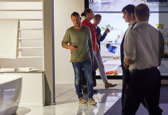 Groep mensen die in gesprek zijn in een moderne winkel met heldere, verlichte displays en eigentijds design.