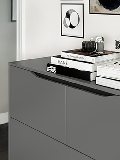 A sleek, modern dresser in a minimalist room, adorned with stylistic books, framed wall art, and a vintage camera, embodying contemporary elegance.