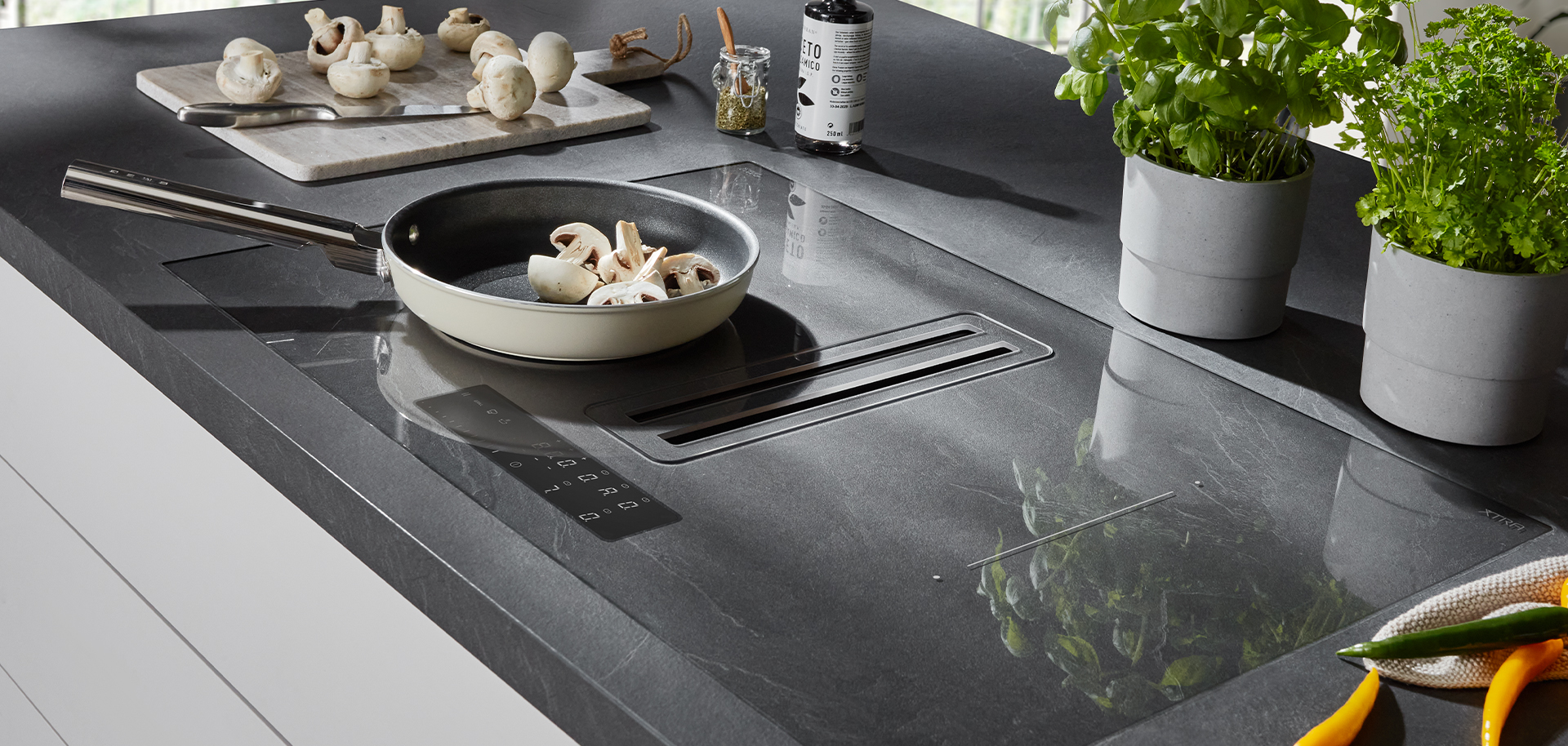 Een moderne keukenwerkblad met een inductiekookplaat met een pan champignons, omringd door verse kruiden en strak, minimalistisch decor.