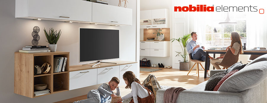 Moderní a stylový obývací pokoj s elegantní stěnnou jednotkou nobilia elements, kde relaxuje pár a dítě hraje na podlaze.