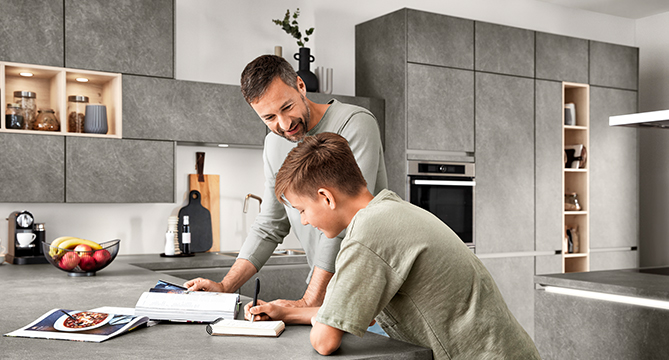 Een vader en zoon doen samen een leuke kooksessie in een moderne keuken, waarbij ze samen een recept volgen voor een gezinsmaaltijd.