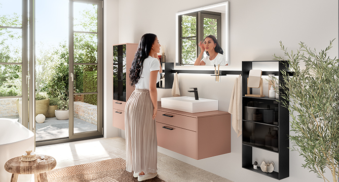 Elegante bagno moderno con una donna che ammira il suo riflesso in uno specchio sopra un elegante mobile, con la luce naturale che filtra da una grande finestra.