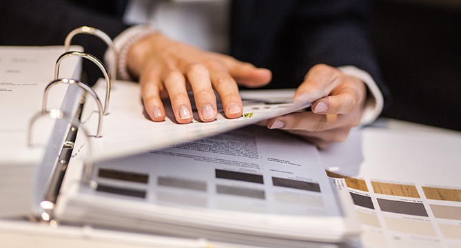 Professional hands reviewing and organizing documents in a binder, showcasing attention to detail and organizational skills in a business setting.