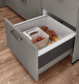 Moderní kuchyňská zásuvka předvádějící organizované úložné řešení s vestavěným oddílem pro čerstvé produkty jako sladké brambory a cibule.