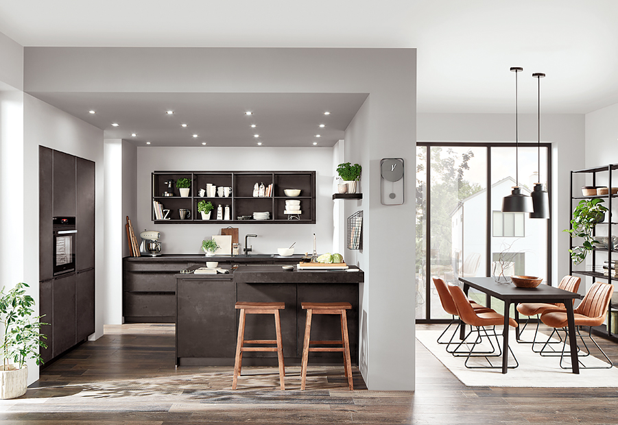 Modern, sleek kitchen with a breakfast bar, built-in appliances, open shelving, and an adjacent dining area with stylish furniture, illuminated by natural light.