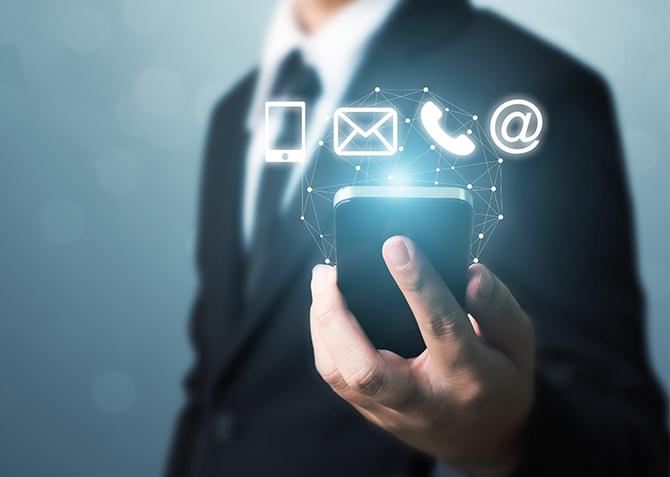 Un professionnel tient un smartphone avec des icônes de communication, symbolisant la connectivité moderne et la technologie numérique dans les affaires.